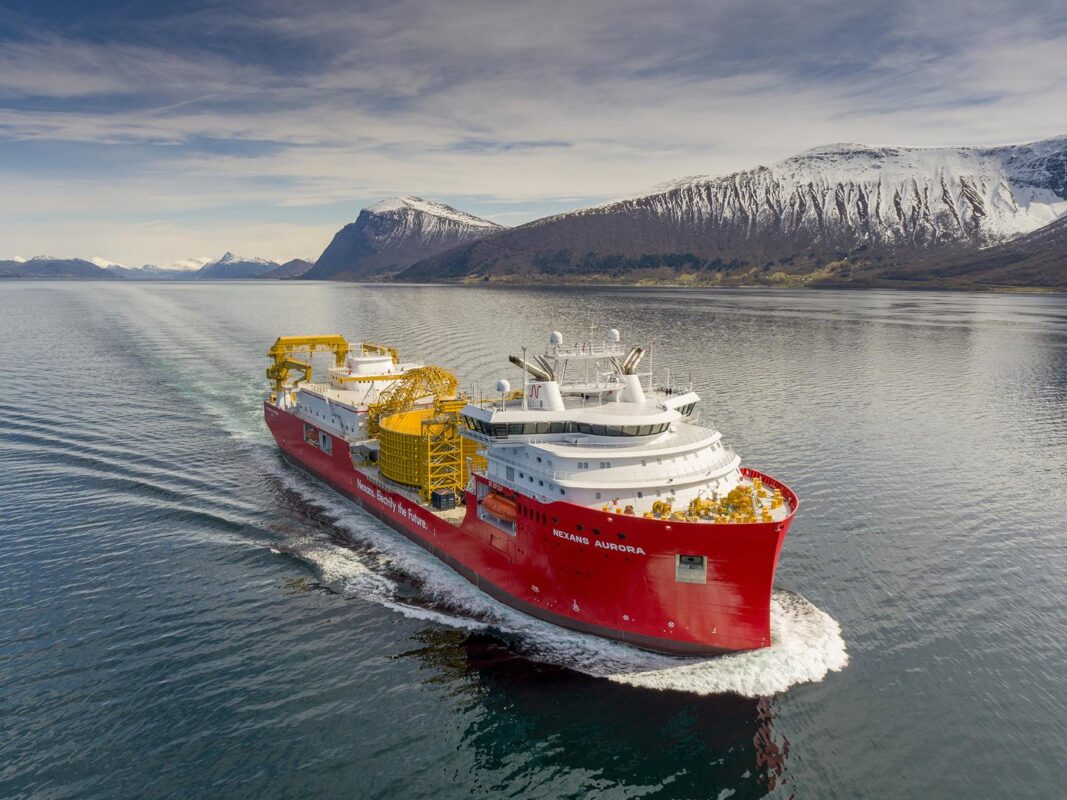Kabelleggingsfartøyet Nexans Aurora seiler i fjorder omgitt av snødekte fjell.